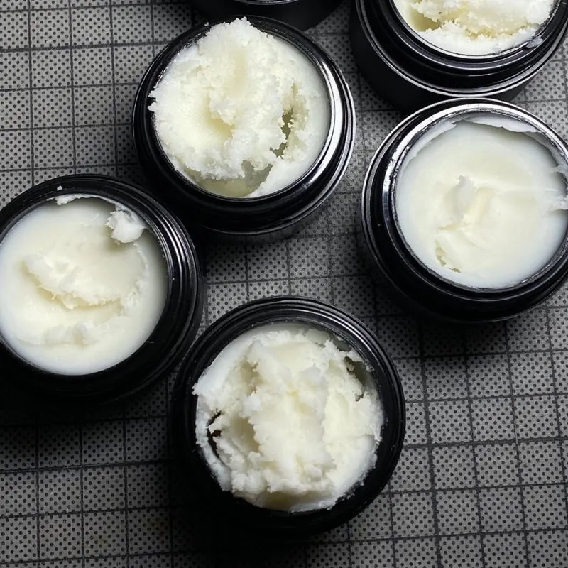 Tattoo aftercare products in open black jars, manufactured for a Belgian brand